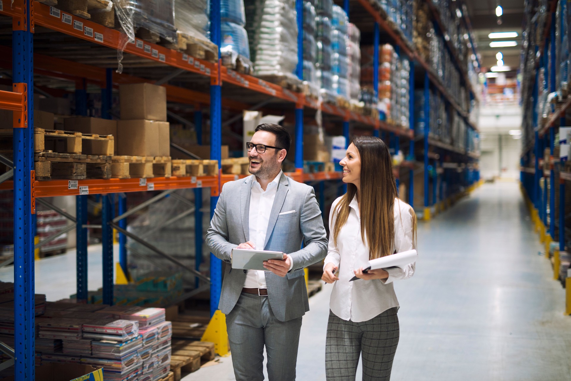 Warehouse managers walking through aisle of warehouse.